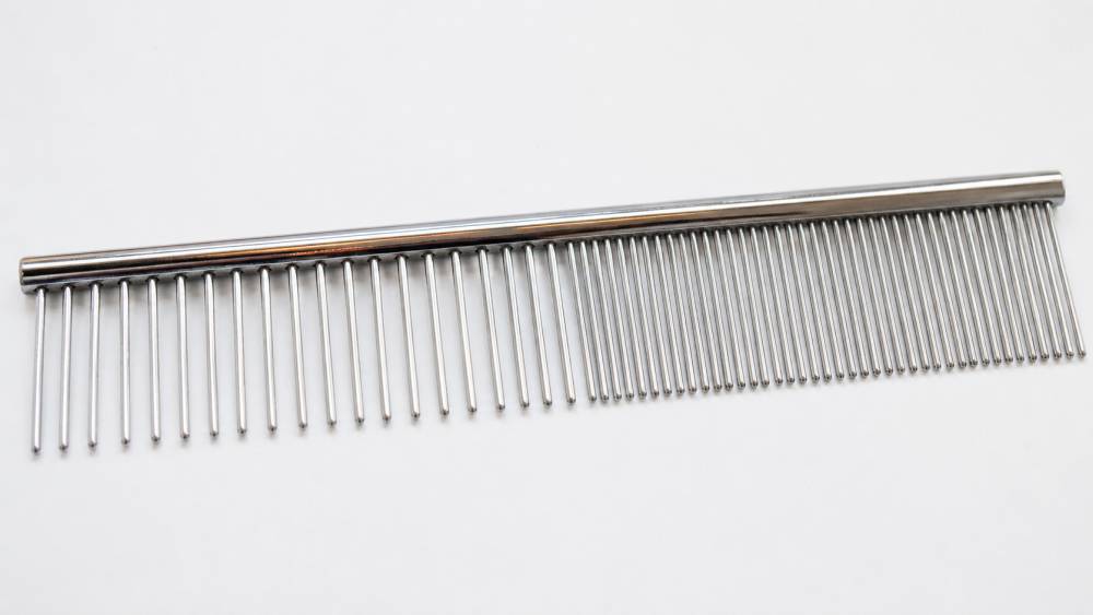 Metallkamm mit feinen und groben Zinken auf hellem Untergrund